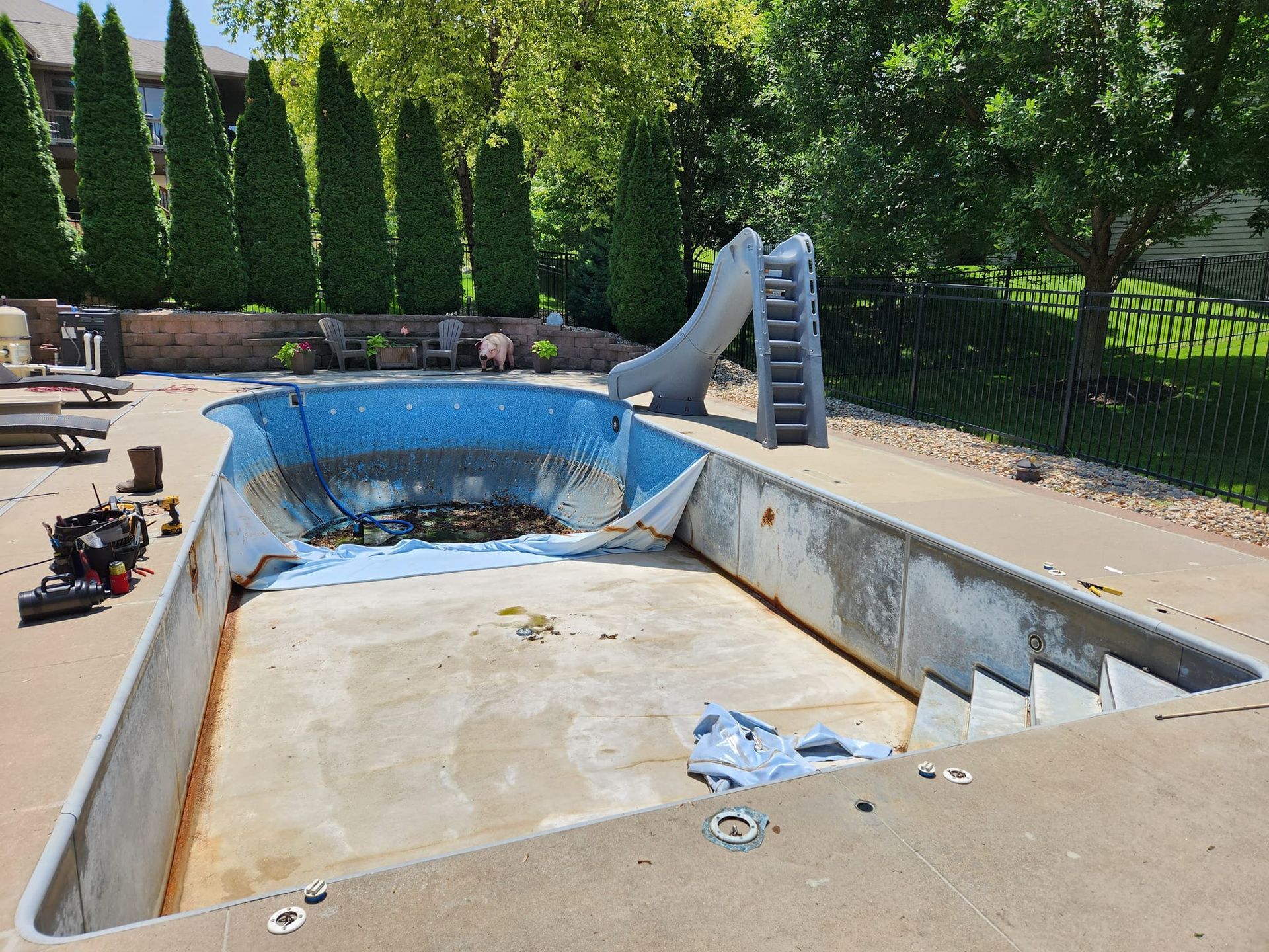 An empty swimming pool with a slide in the backyard.