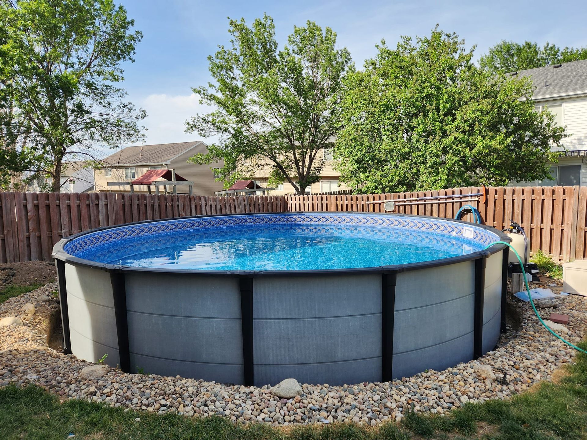 A large swimming pool is sitting in the backyard of a house.