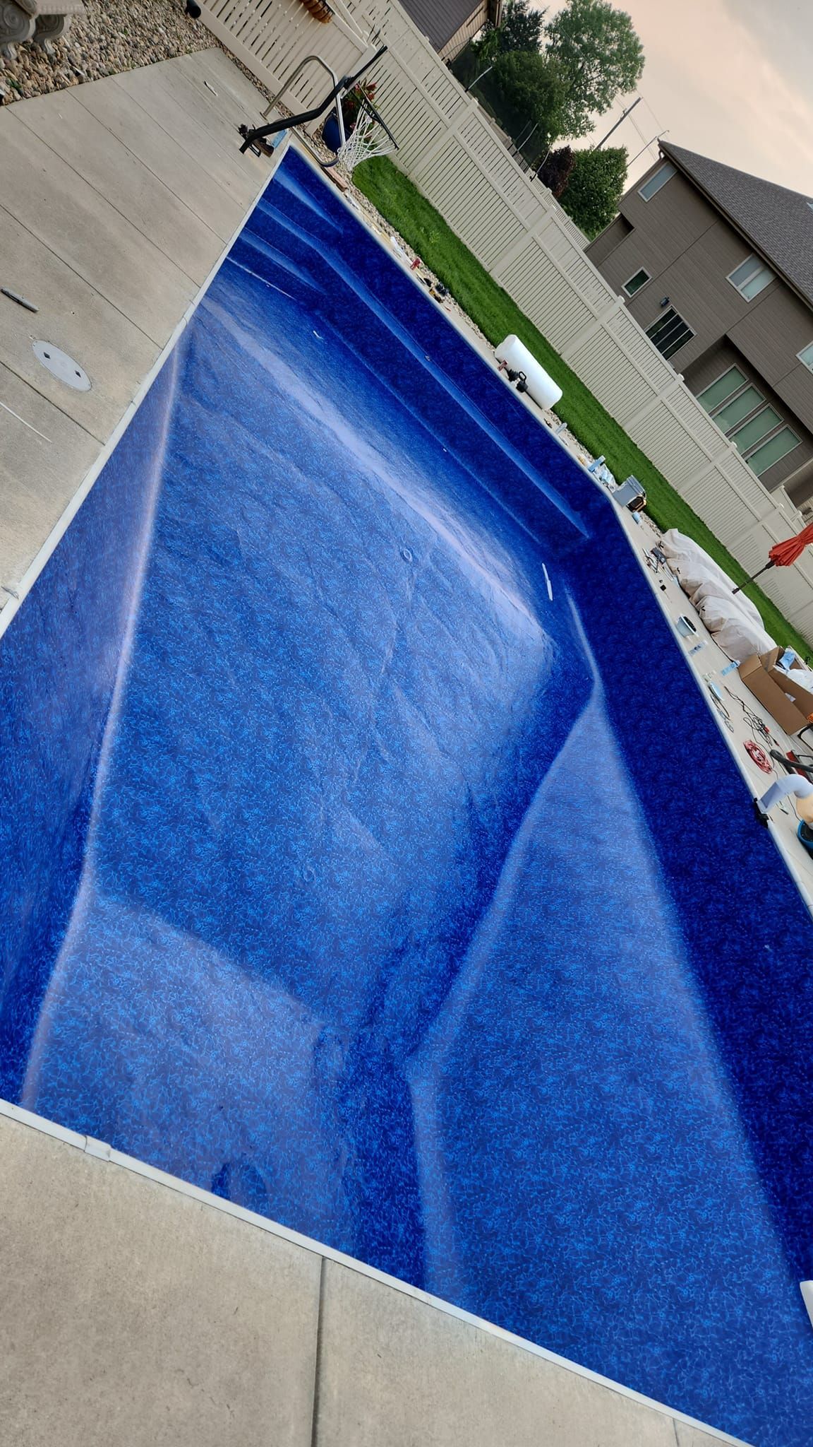 A large blue swimming pool is sitting on top of a concrete patio.