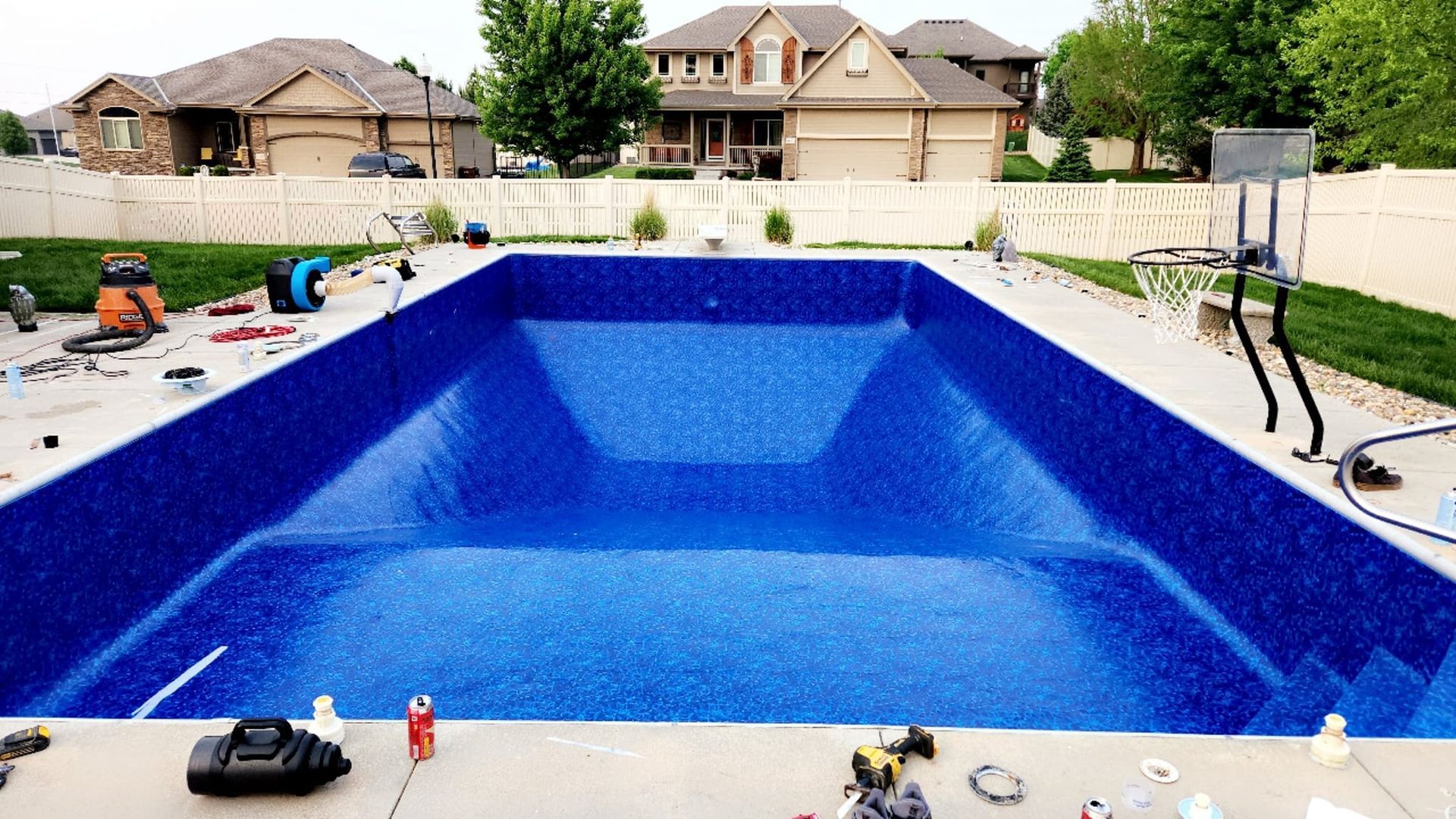 A large swimming pool is being built in the backyard of a house.