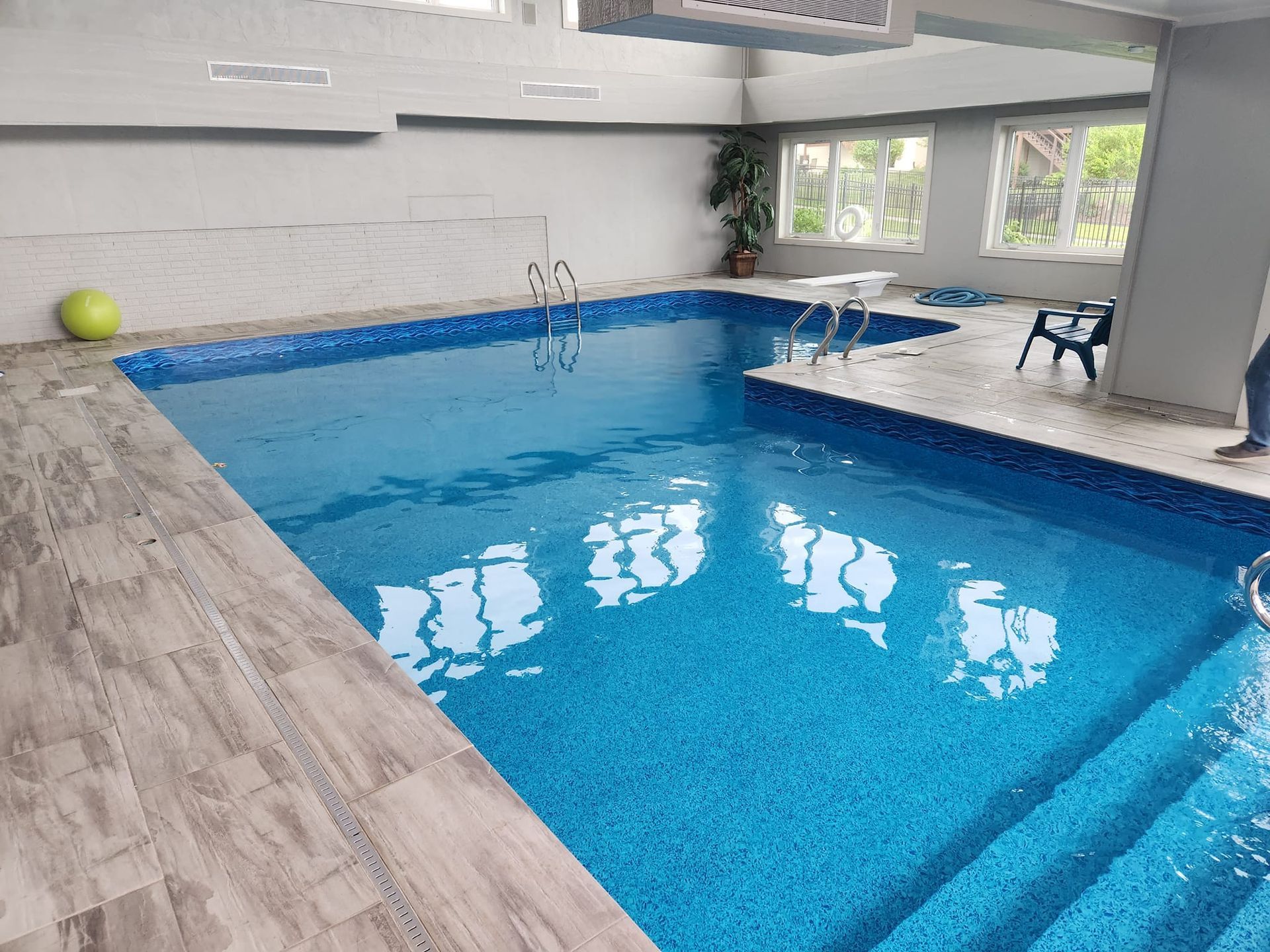 There is a large indoor swimming pool with stairs leading to it.