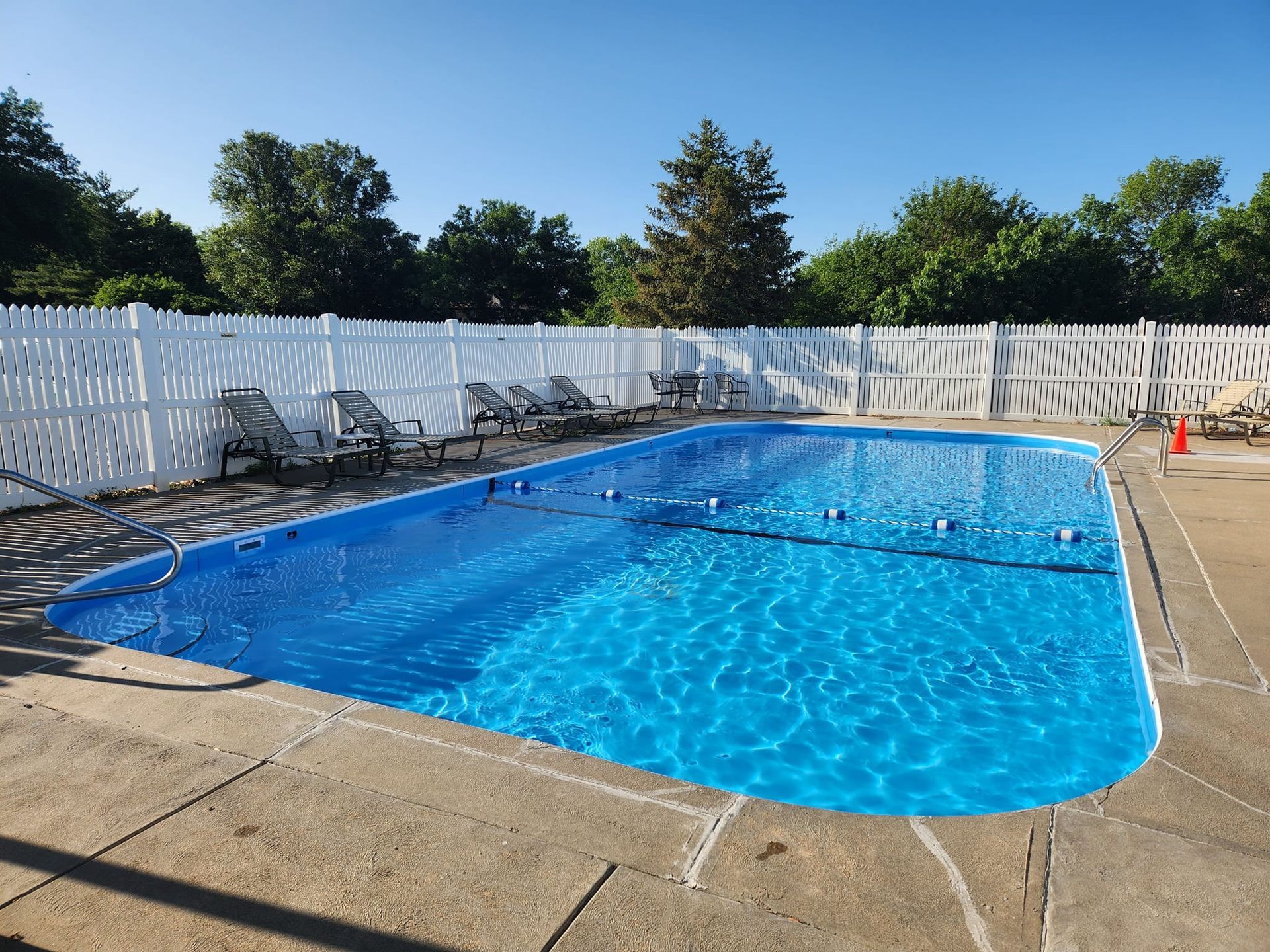 A large swimming pool with a white fence around it