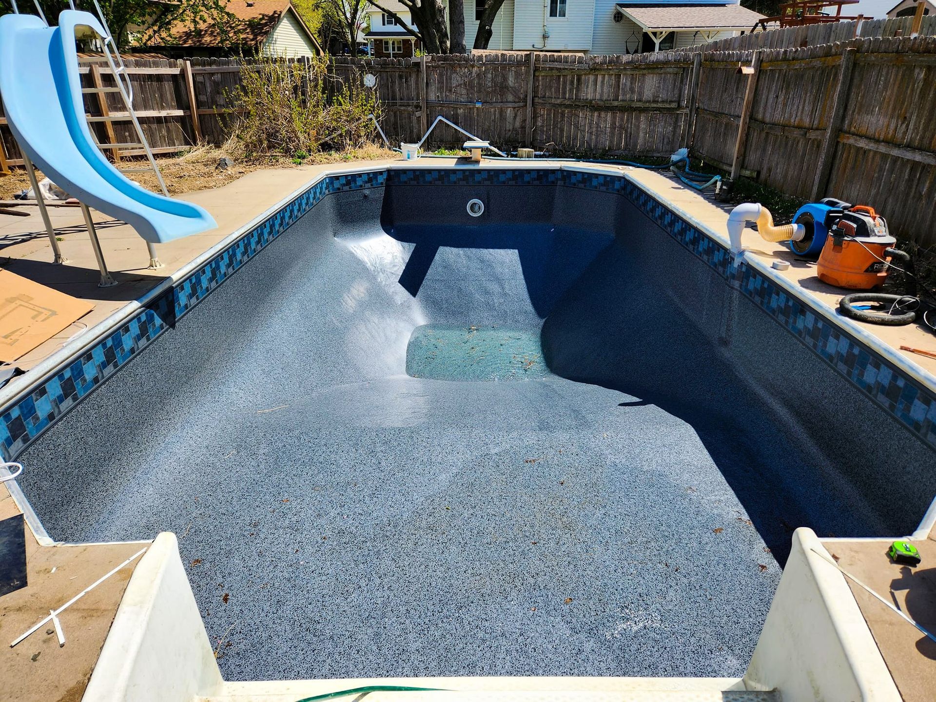 A swimming pool is being built in a backyard with a slide.