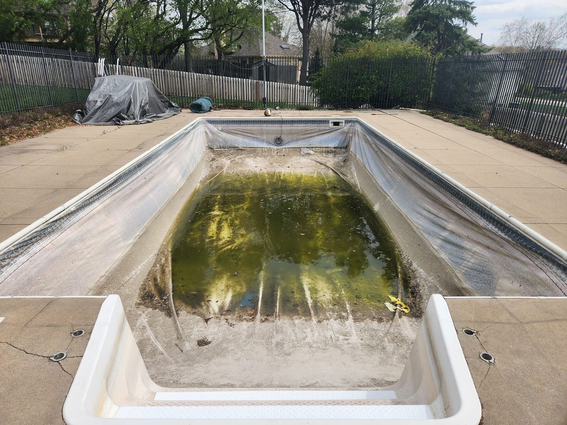 An empty swimming pool with a white staircase leading to it.