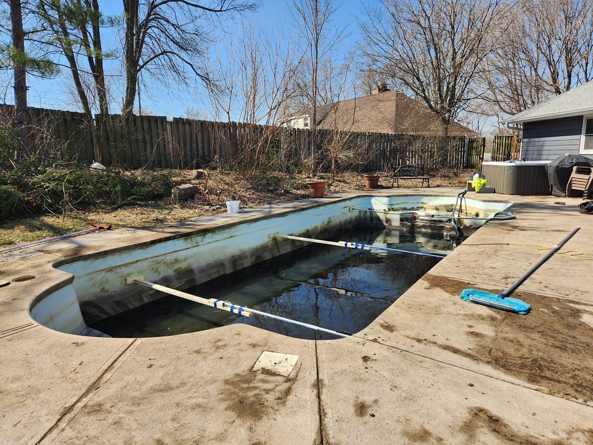 An empty swimming pool with a broom on the side of it.
