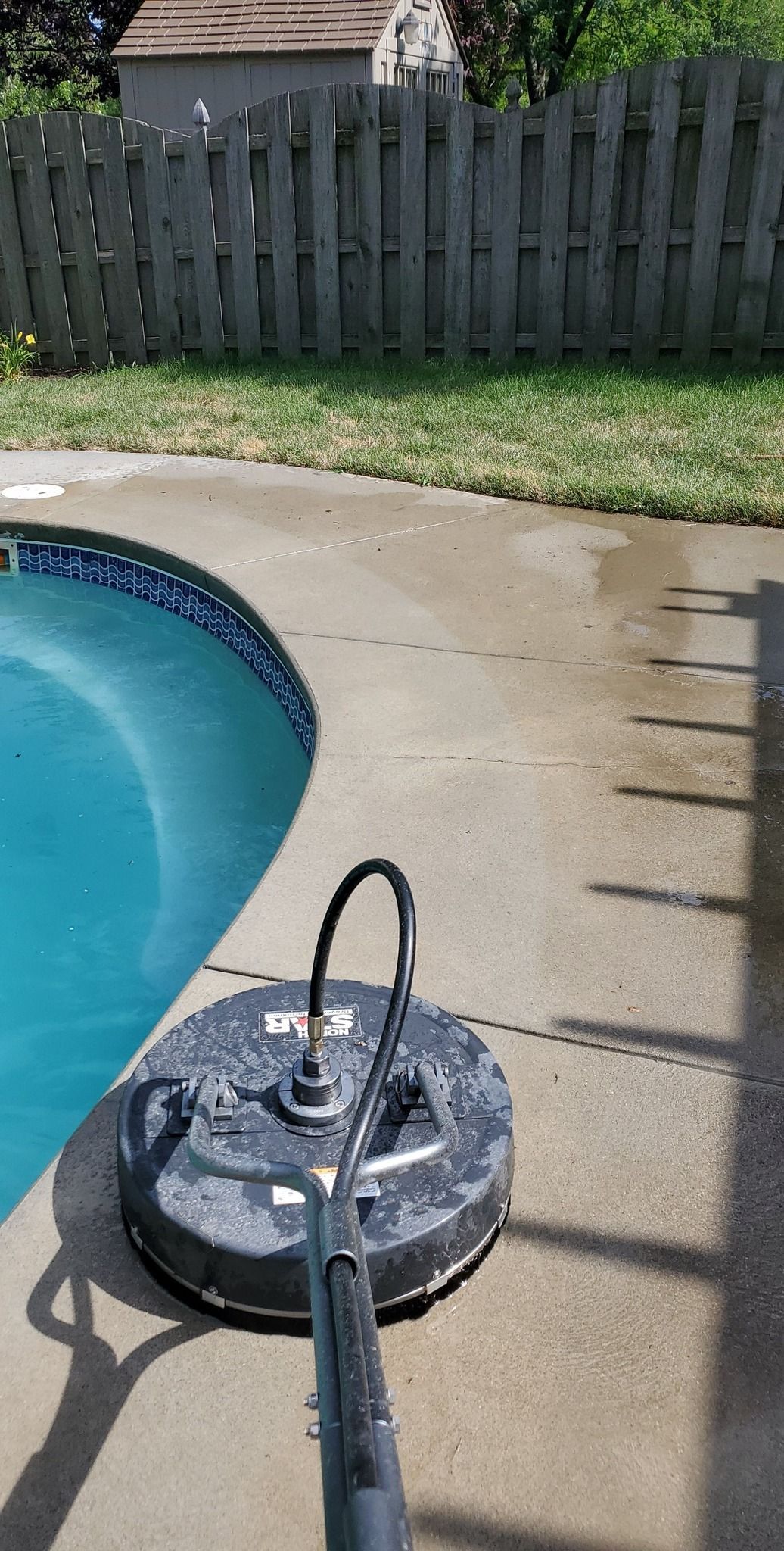 A pressure washer is sitting on a concrete patio next to a pool.