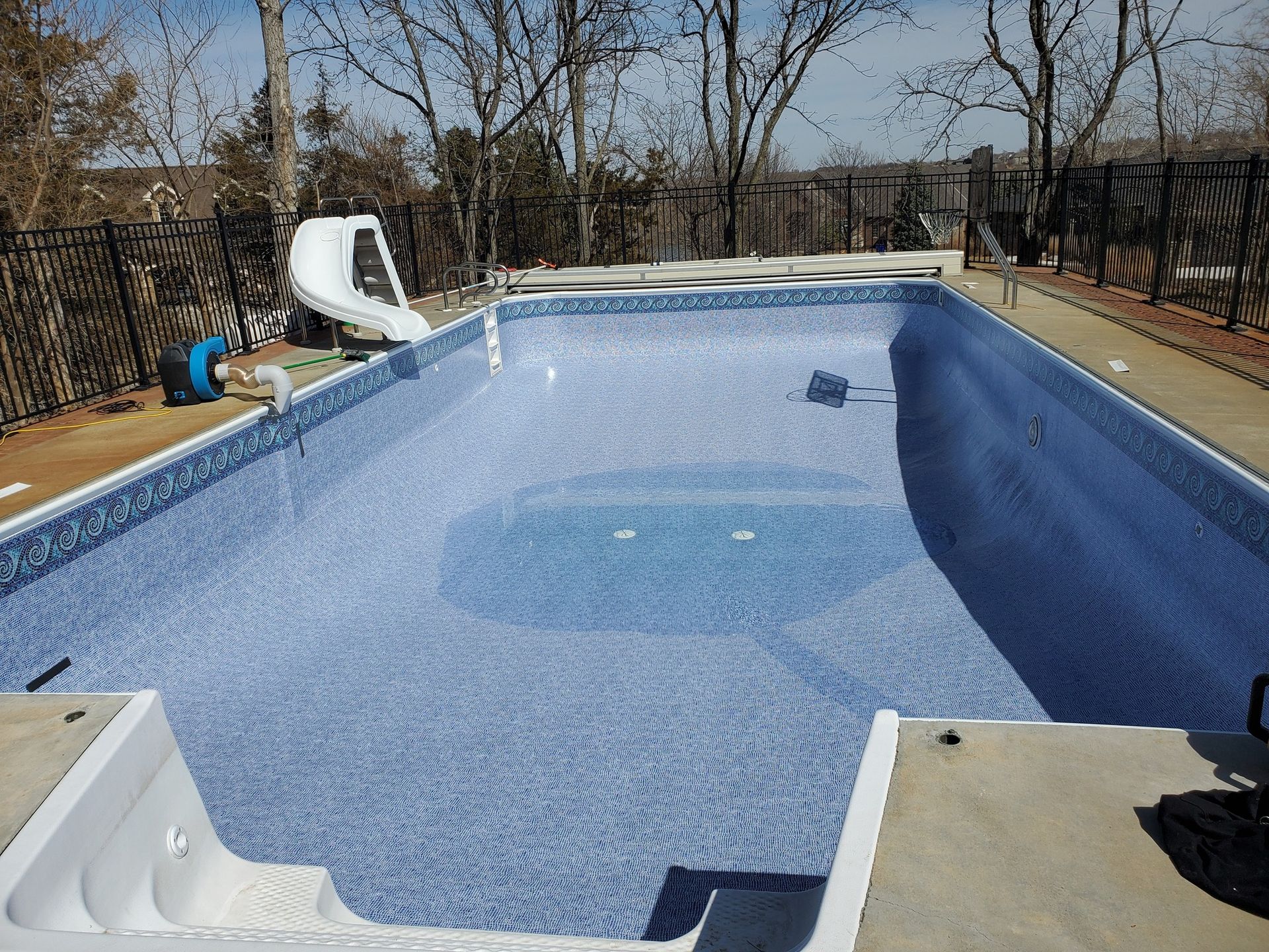 An empty swimming pool with a slide in the background