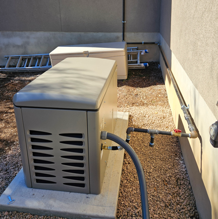 Outdoor HVAC unit beside a stucco wall on a gravel rooftop, with a ladder and conduit nearby