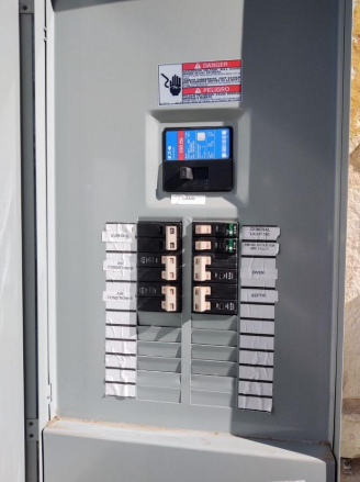 Apartment electrical panel with breaker switches and a digital meter display.