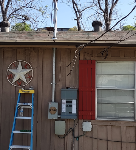 House exterior with star wall decor, ladder, utility boxes, and red shutters beside a window