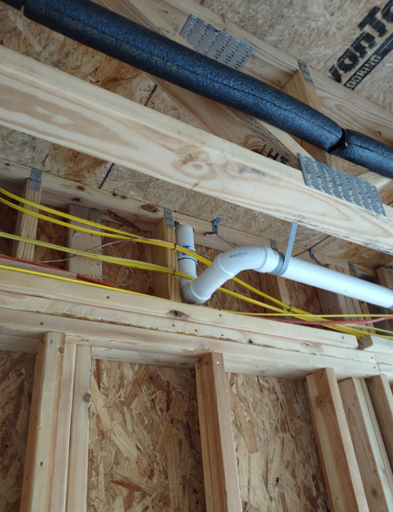 Framing lumber and PVC plumbing pipes inside a house under construction