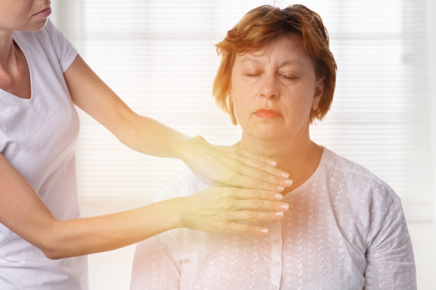 Woman receiving energy healing with hands hovering over her throat; yellow aura visible.