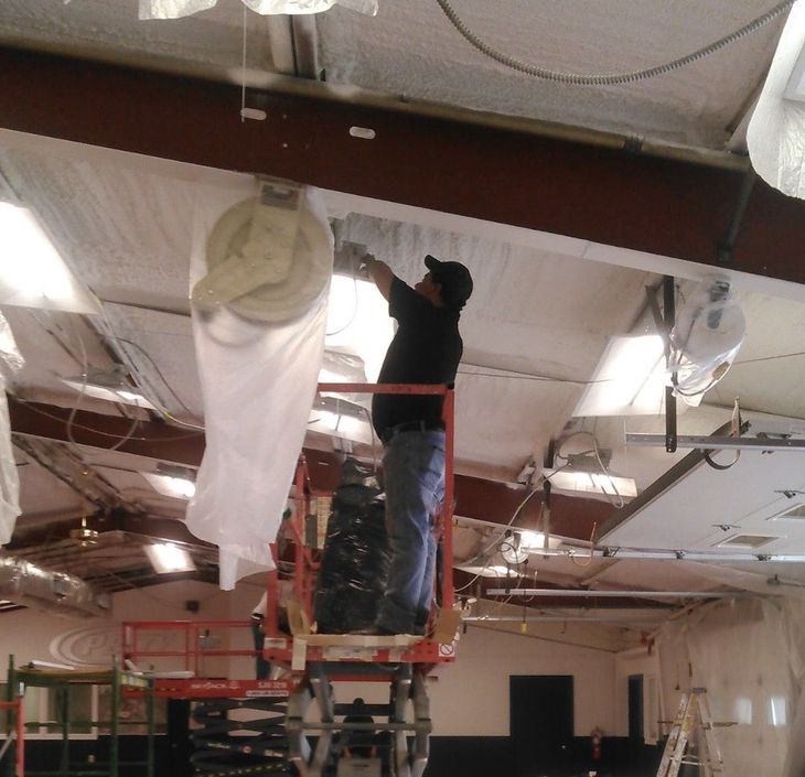 Worker on a lift installing ceiling material in an indoor construction area