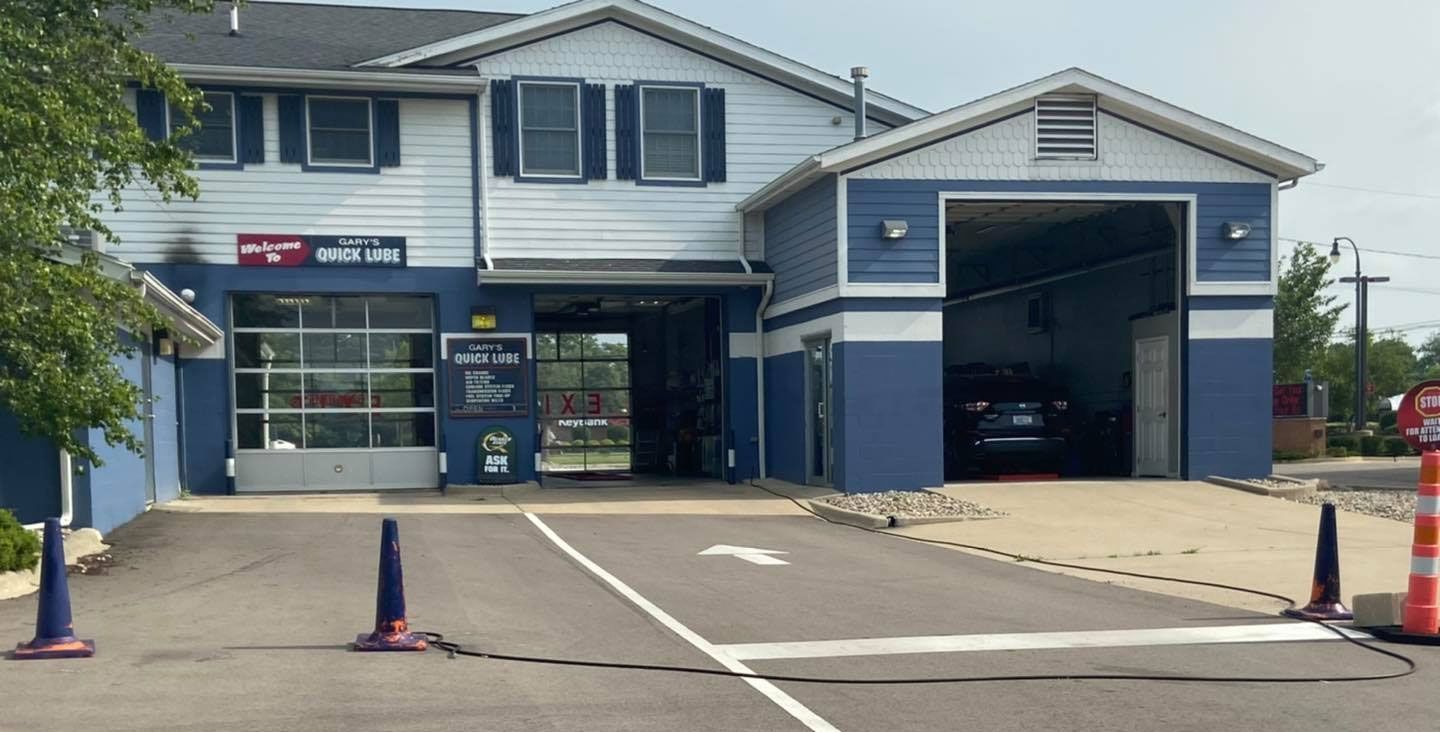 Oil being poured from a blue container into a car engine.
