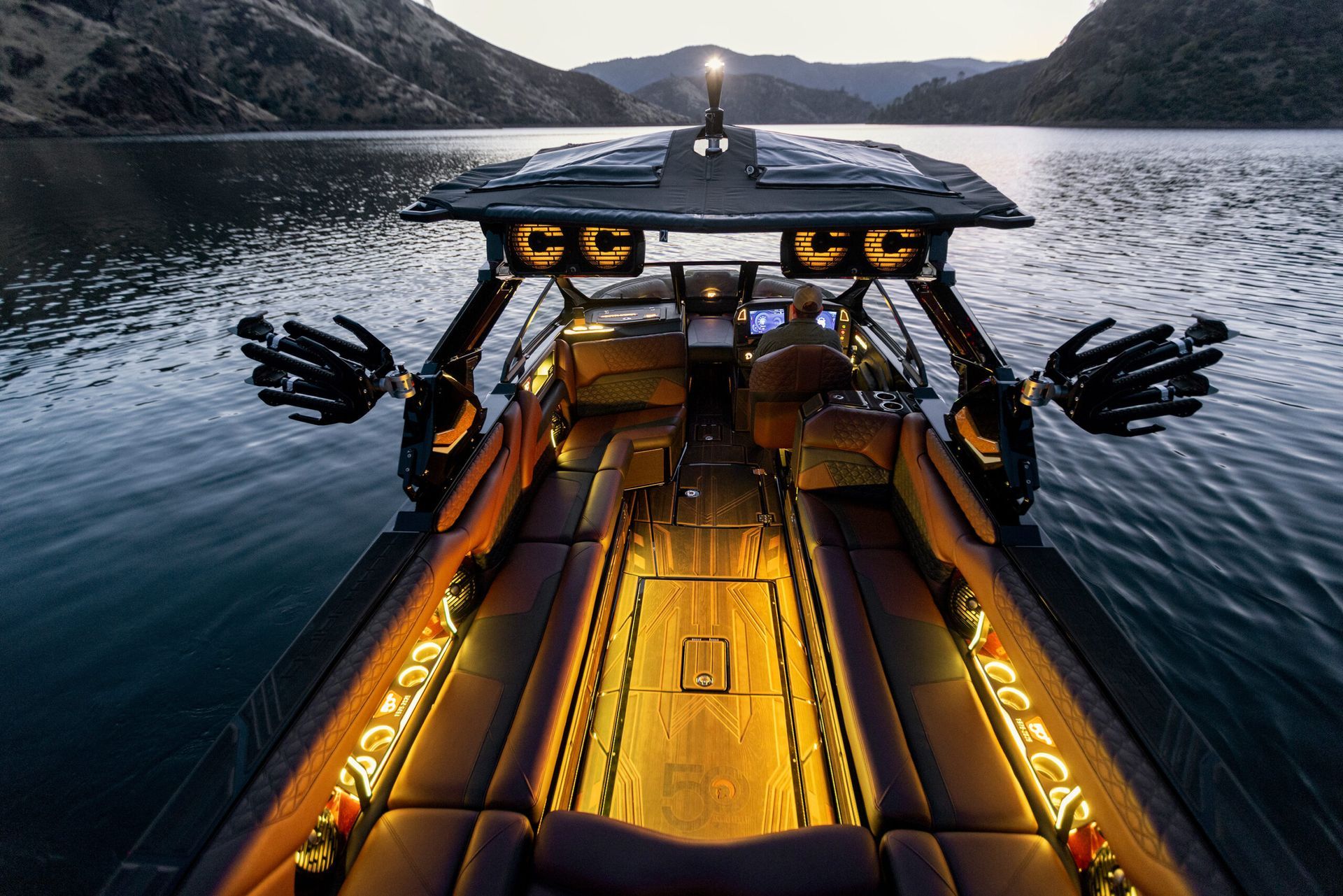 Luxury boat on a lake at dusk. Features include lit interior, black arms, and a top-mounted light.