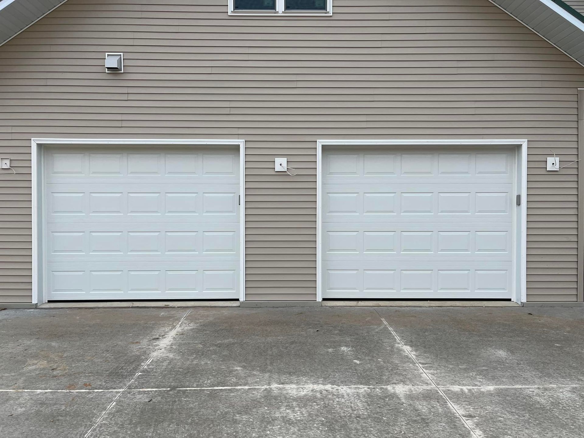 Two white garage doors on the side of a house