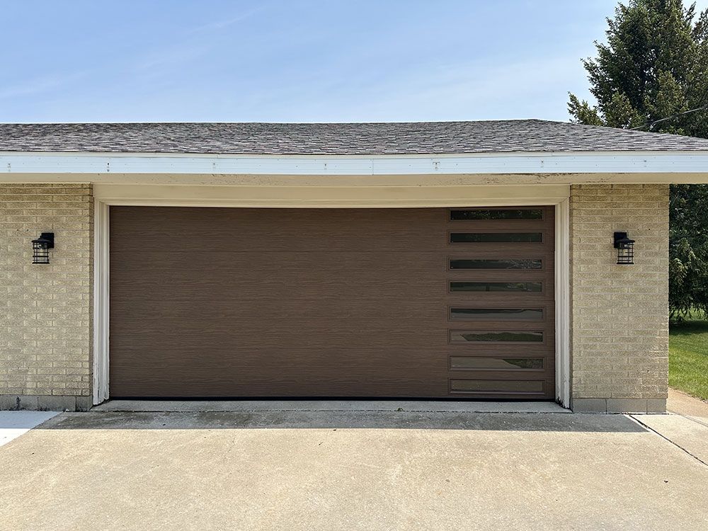 A garage with a brown garage door and a brick wall.