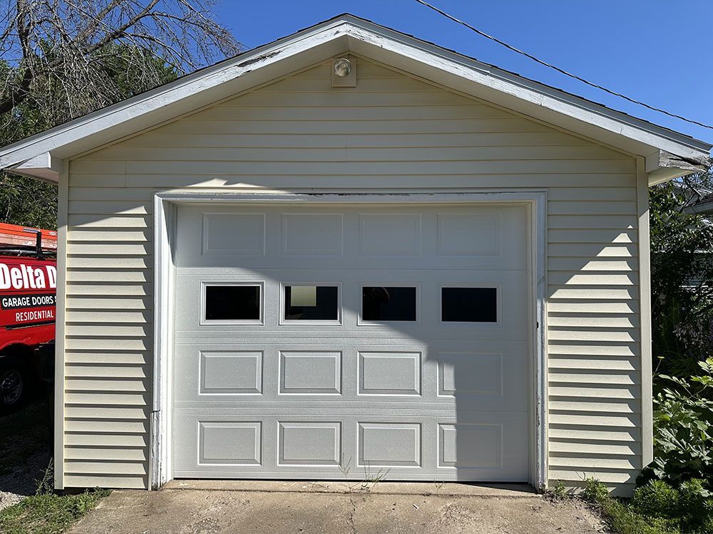 A white garage door with a red truck parked in front of it.