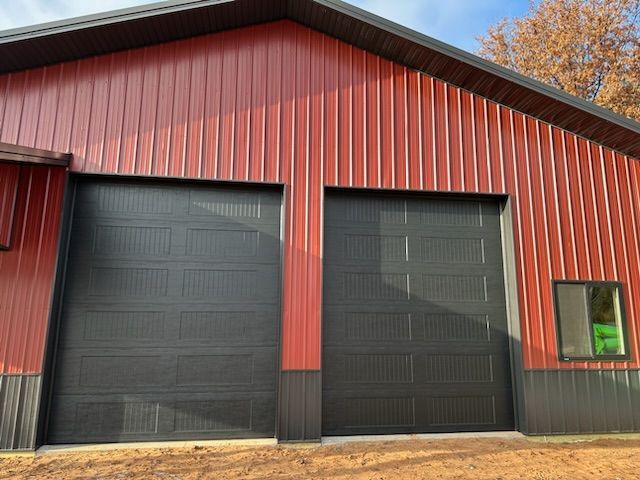 A red building with black garage doors and a window.
