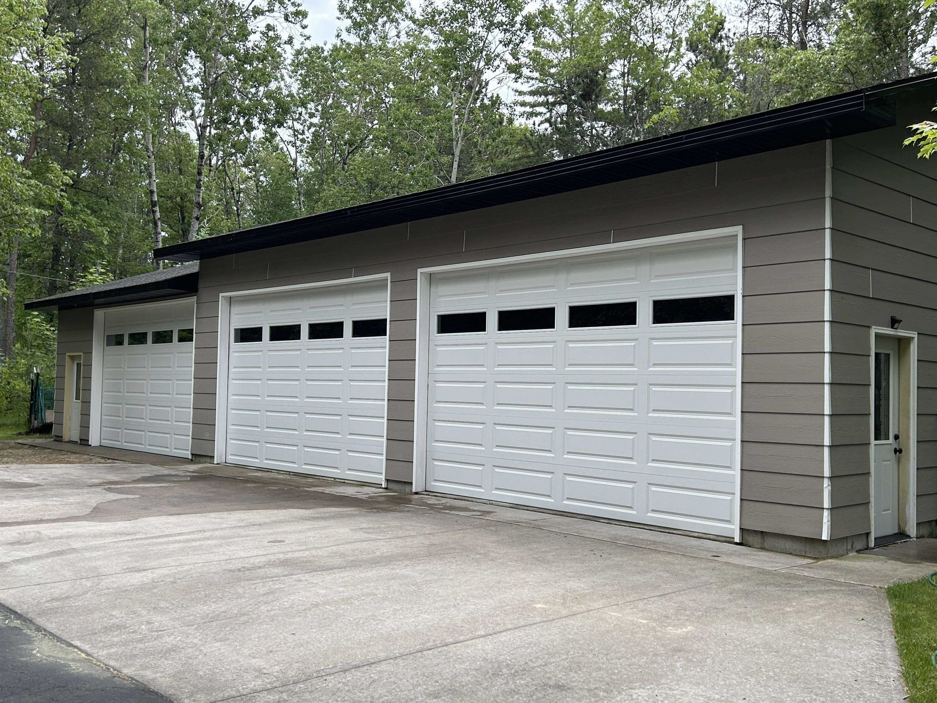 There are three garage doors on the side of a building.