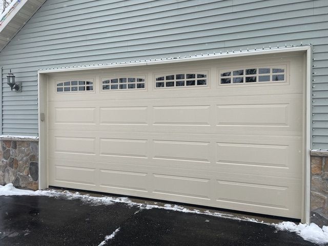 A white garage door is open in front of a house