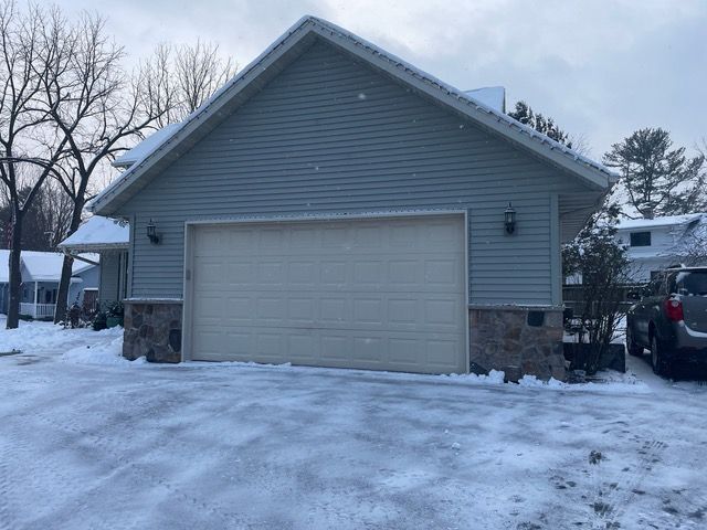 A garage with a white door is covered in snow