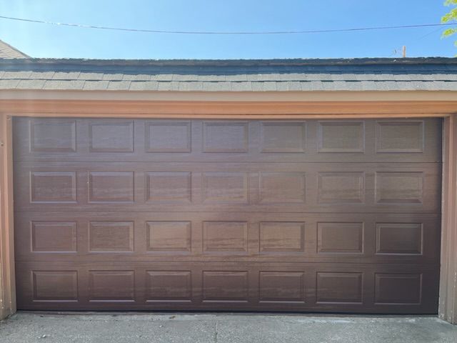 A brown garage door is open on a sunny day.