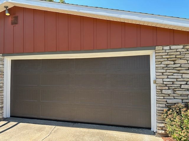 A garage door with a red siding and a stone wall