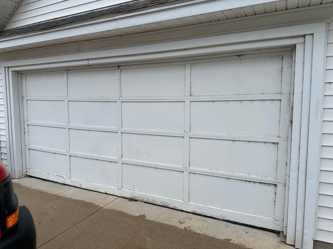A white garage door is open and a car is parked in front of it.