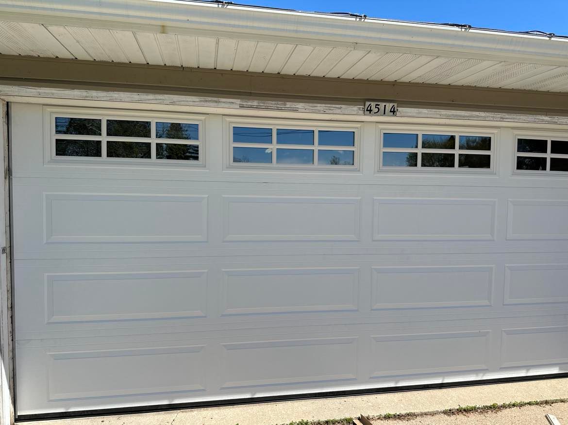 A white garage door with a lot of windows on a house.