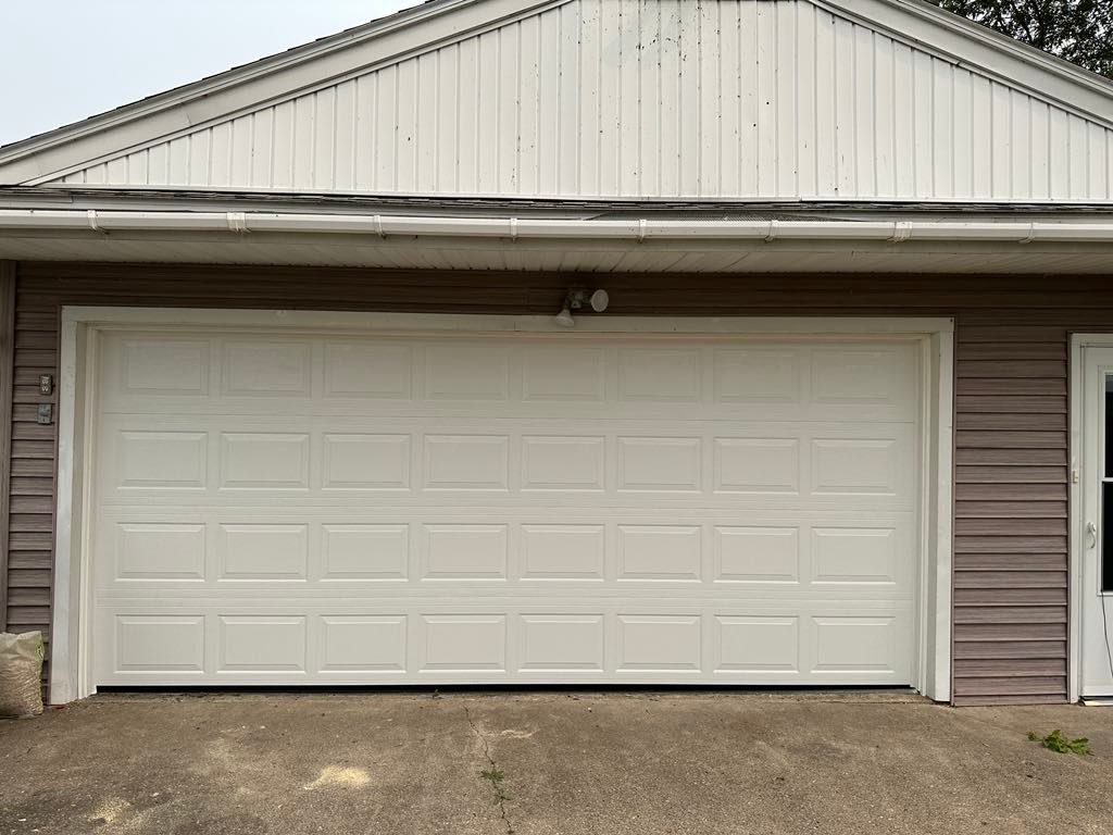 A large white garage door is open on the side of a house.