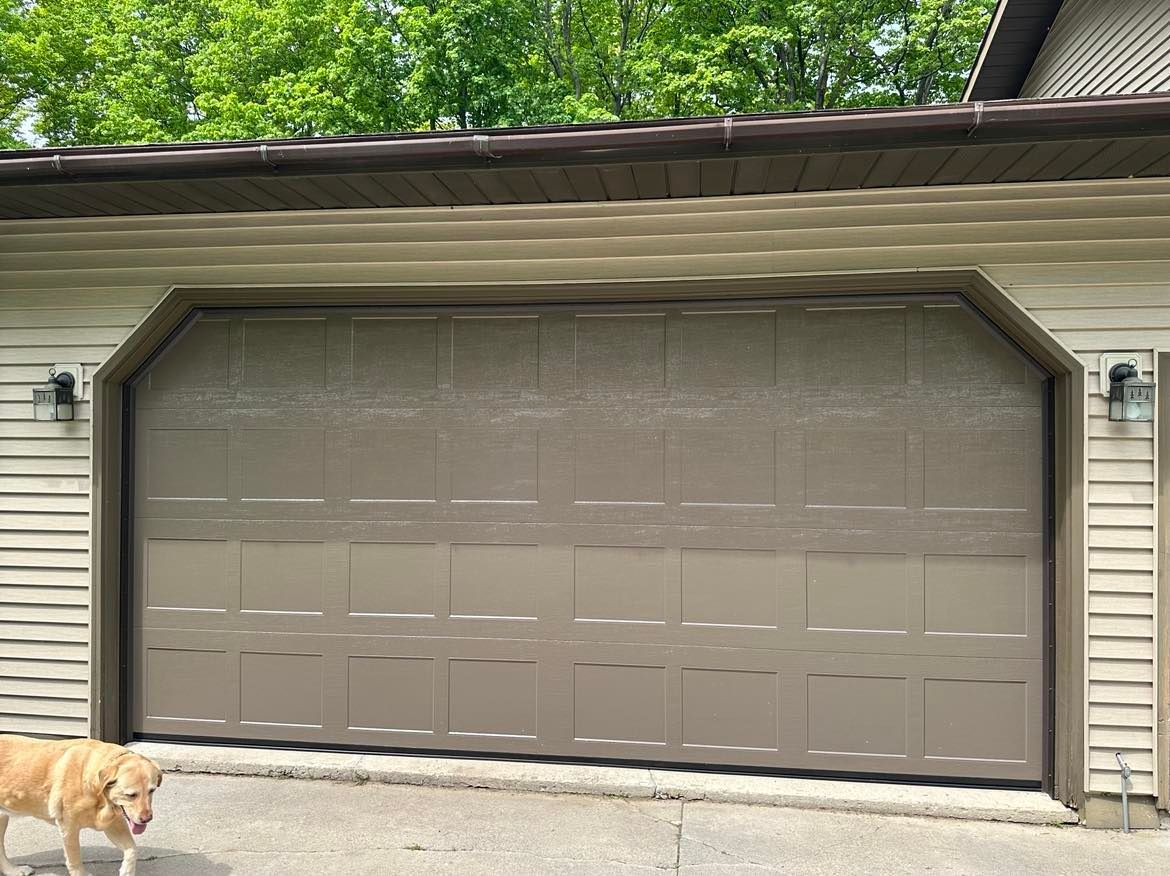 A dog is standing in front of a garage door.