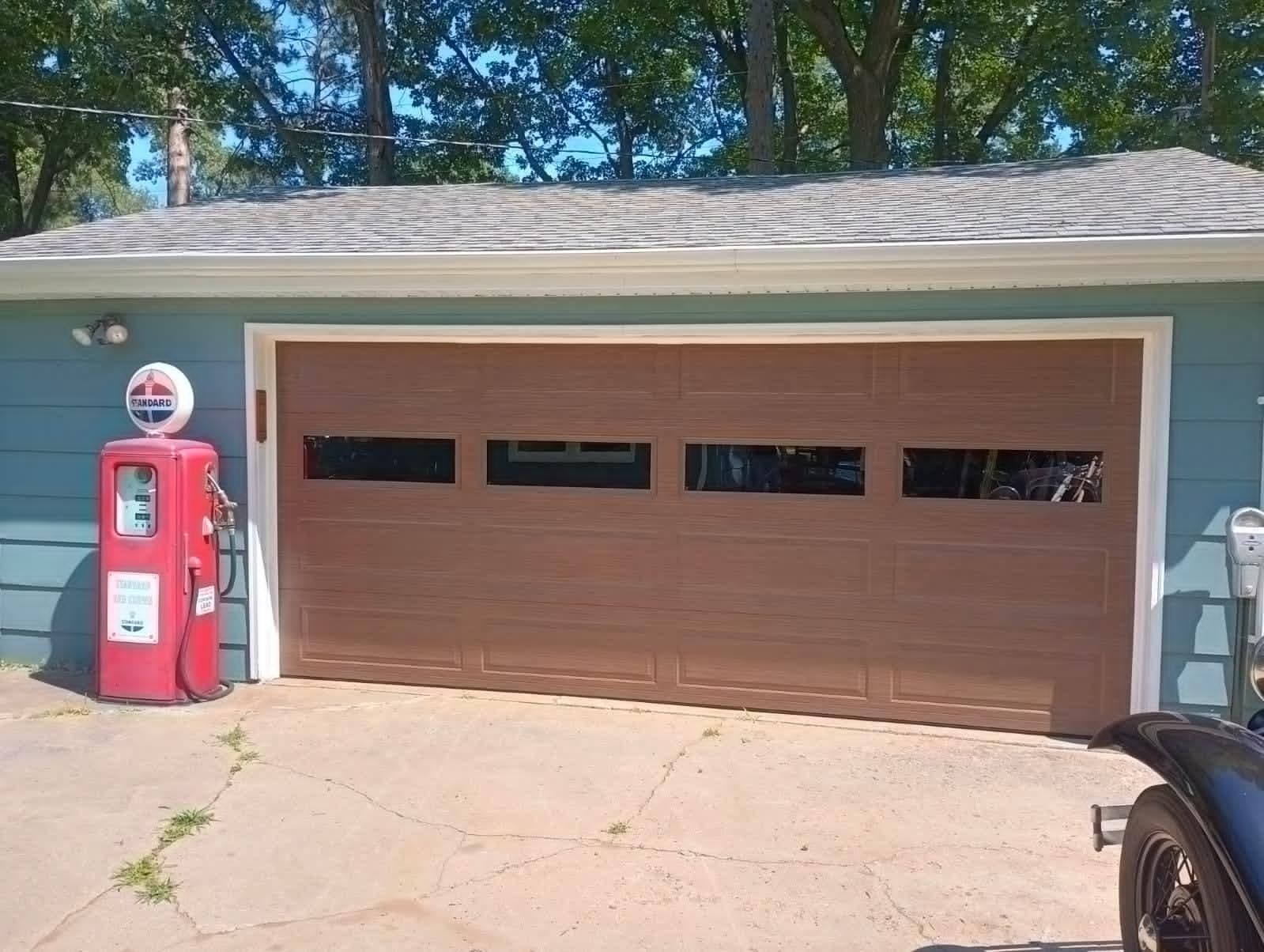 A red gas pump is in front of a garage door.