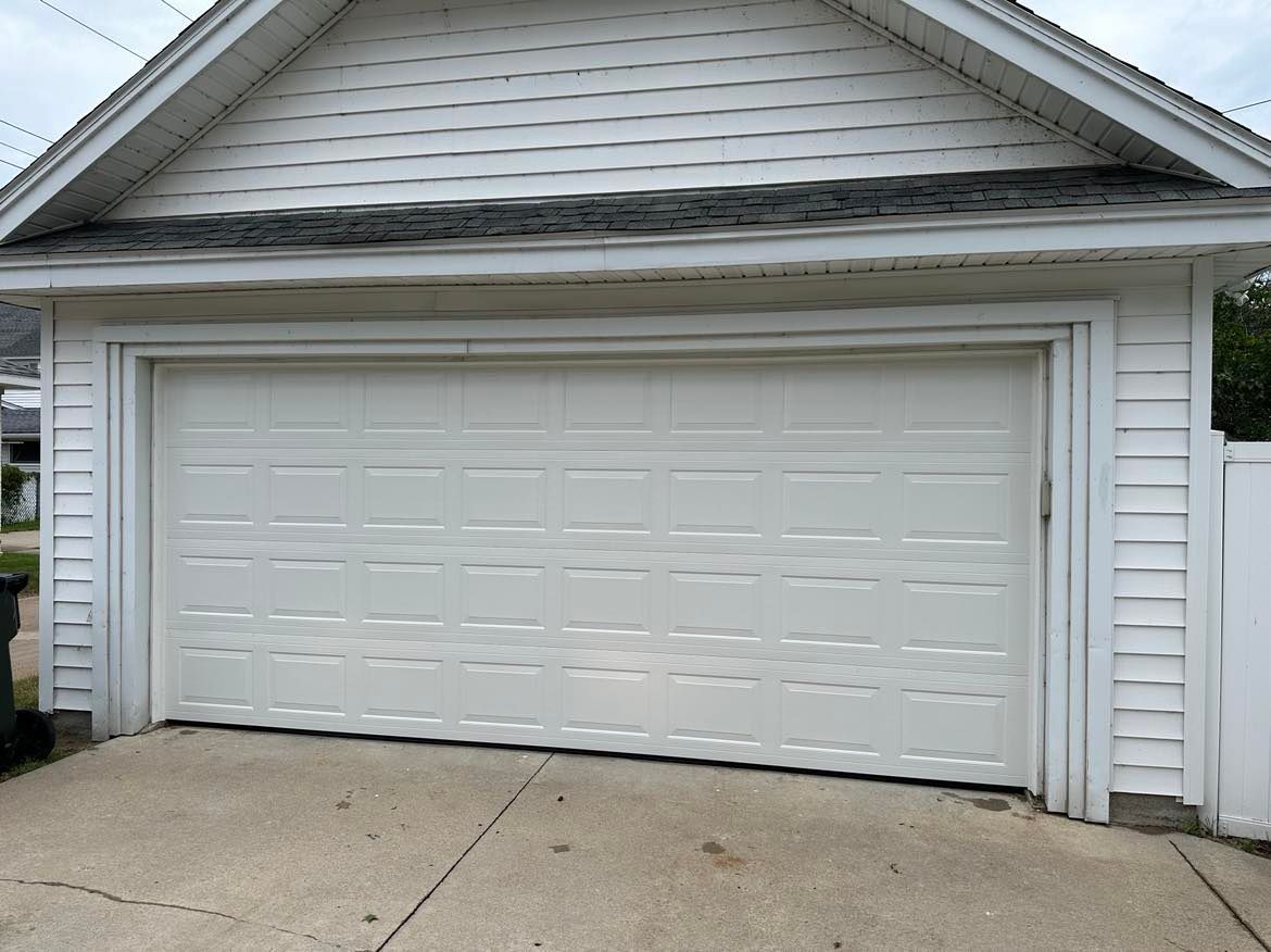 A white garage door is open in front of a white house.