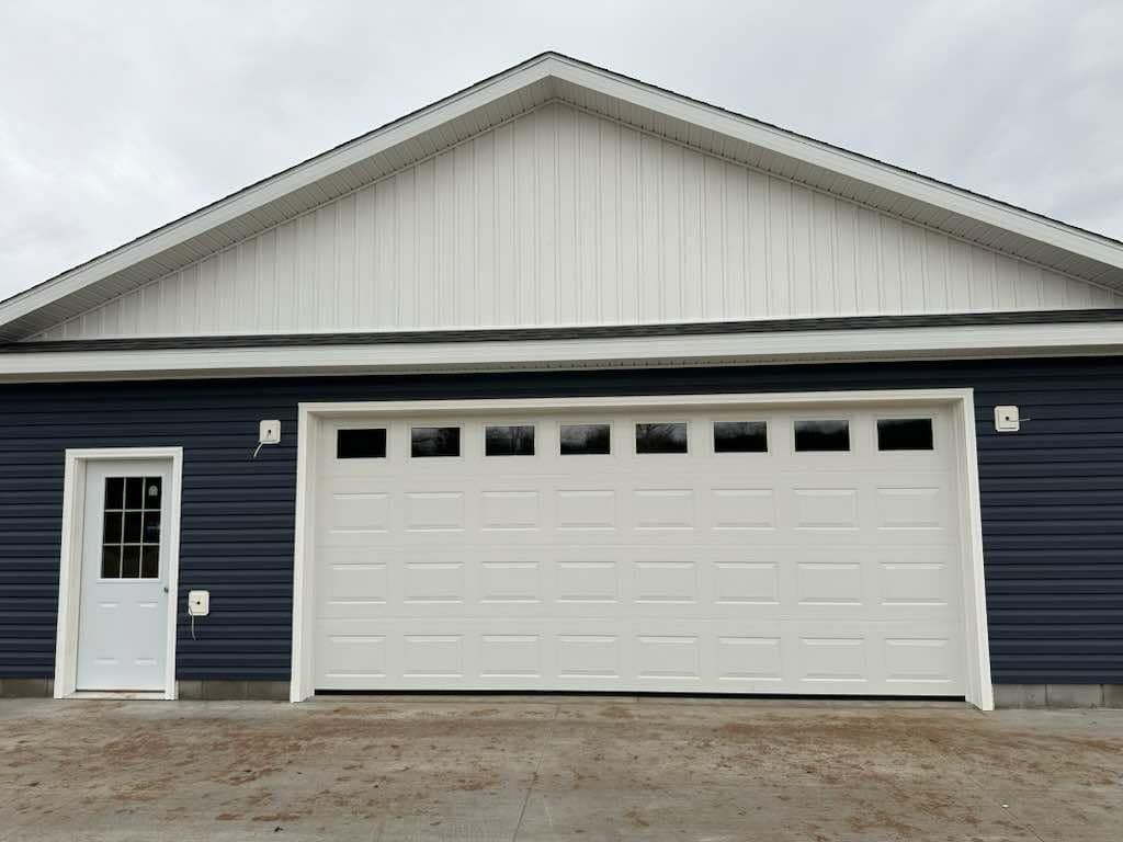A blue house with a white garage door and a white door.