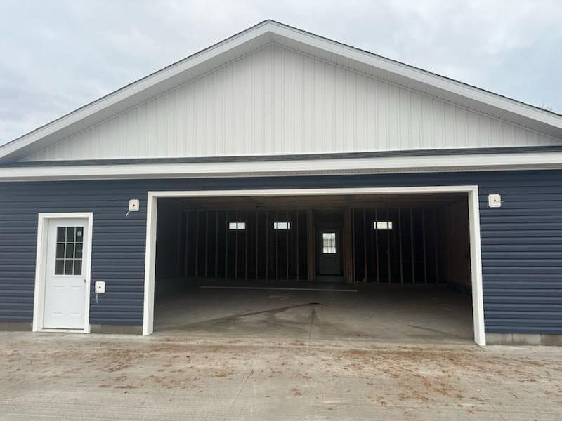 A large garage with a white roof and blue siding is being built.