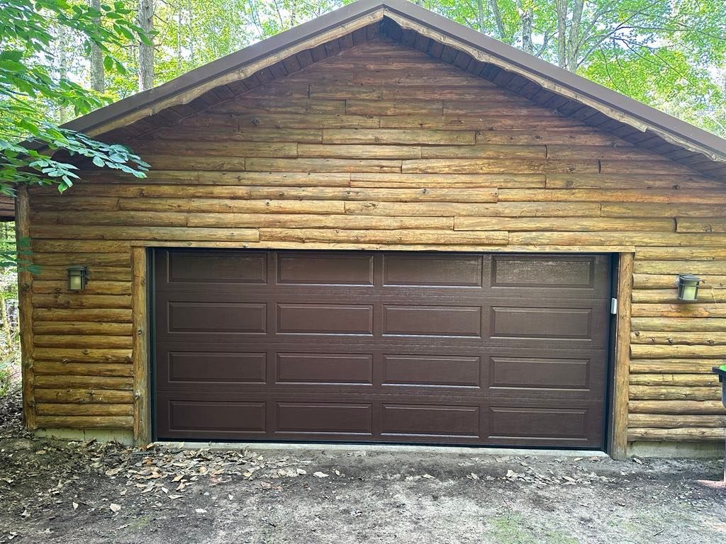 A garage with a log siding and a brown garage door.