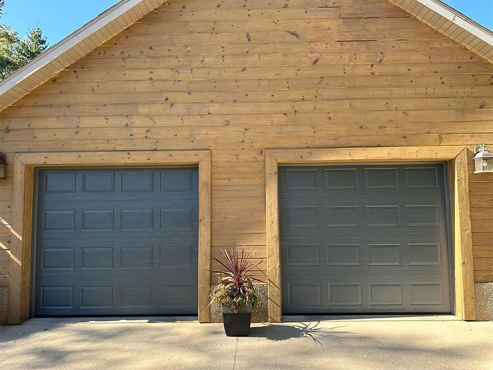 A wooden garage with two gray garage doors