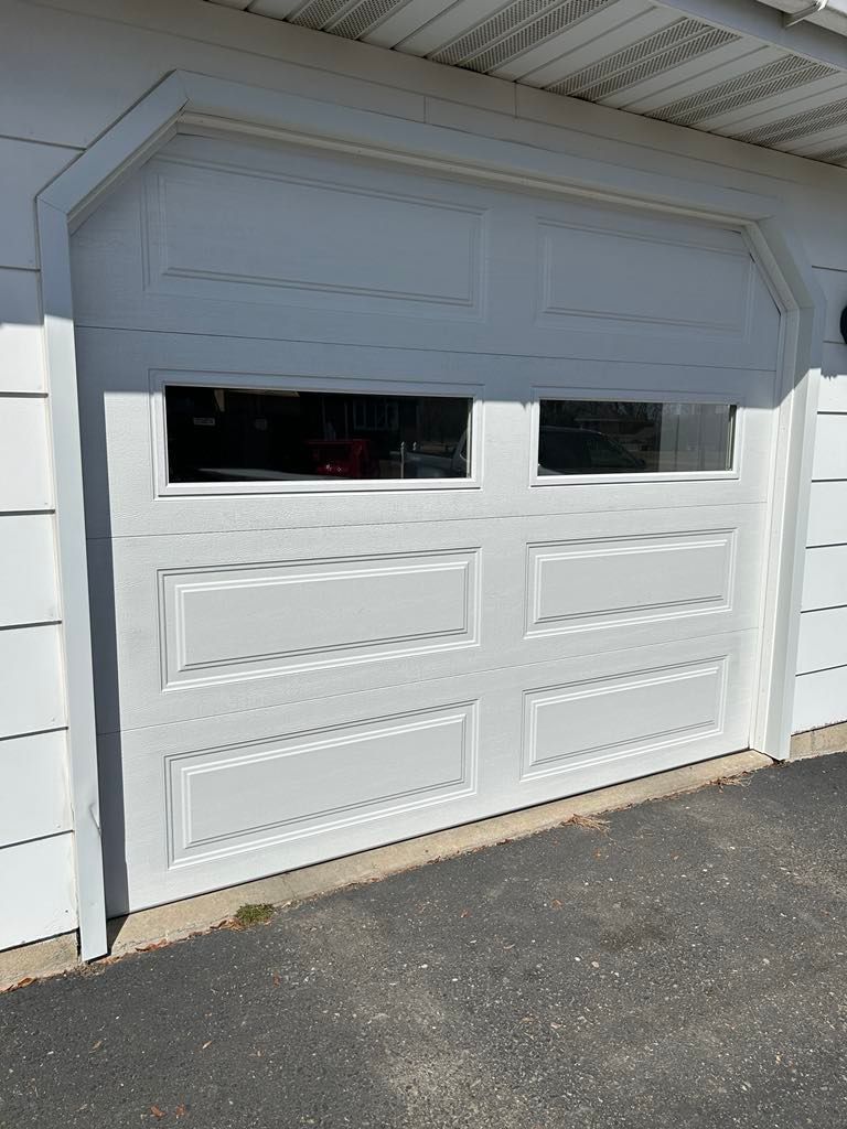 A white garage door with a window in it is open.