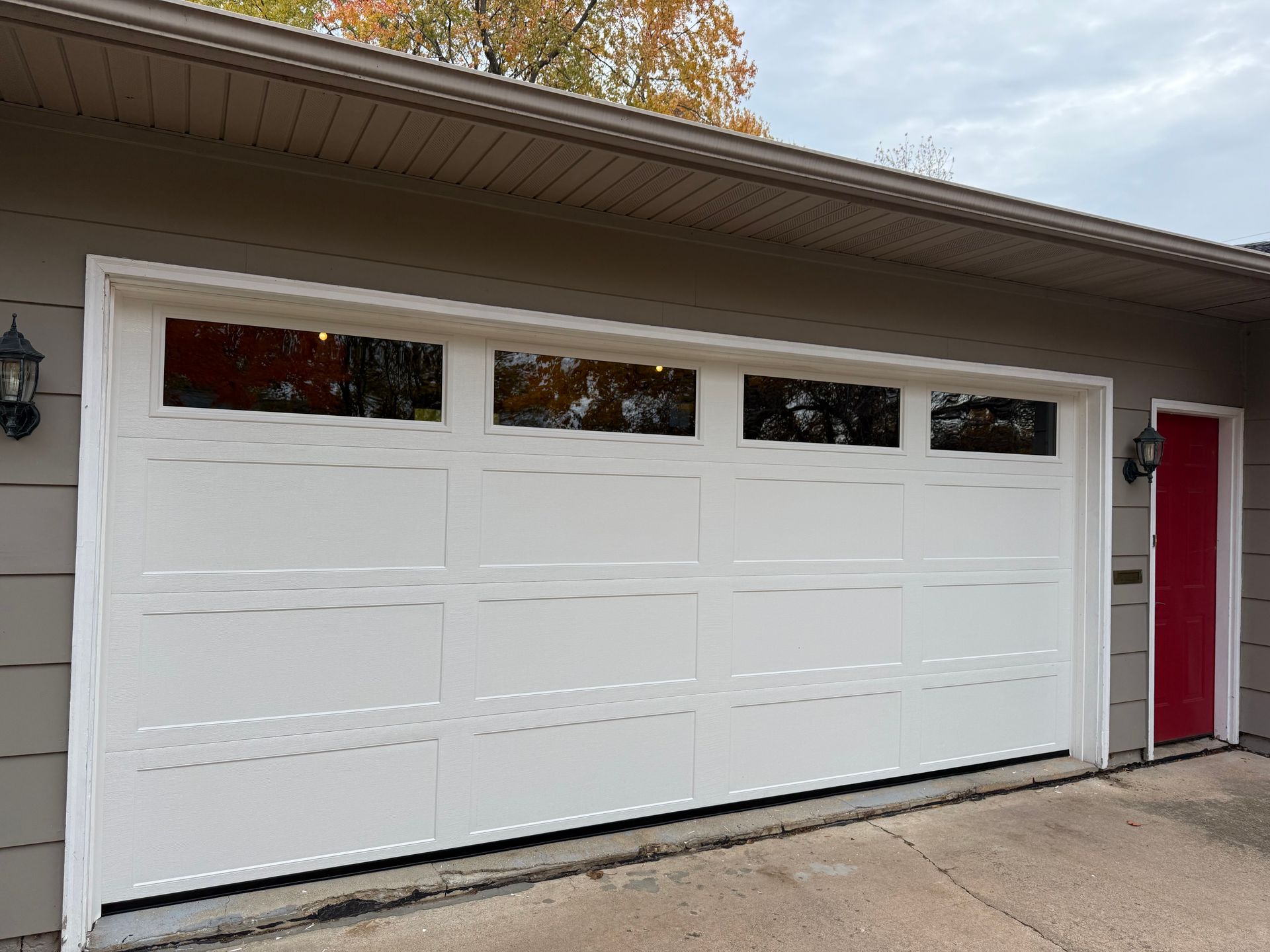 White garage door with glass panels; next to a red door.