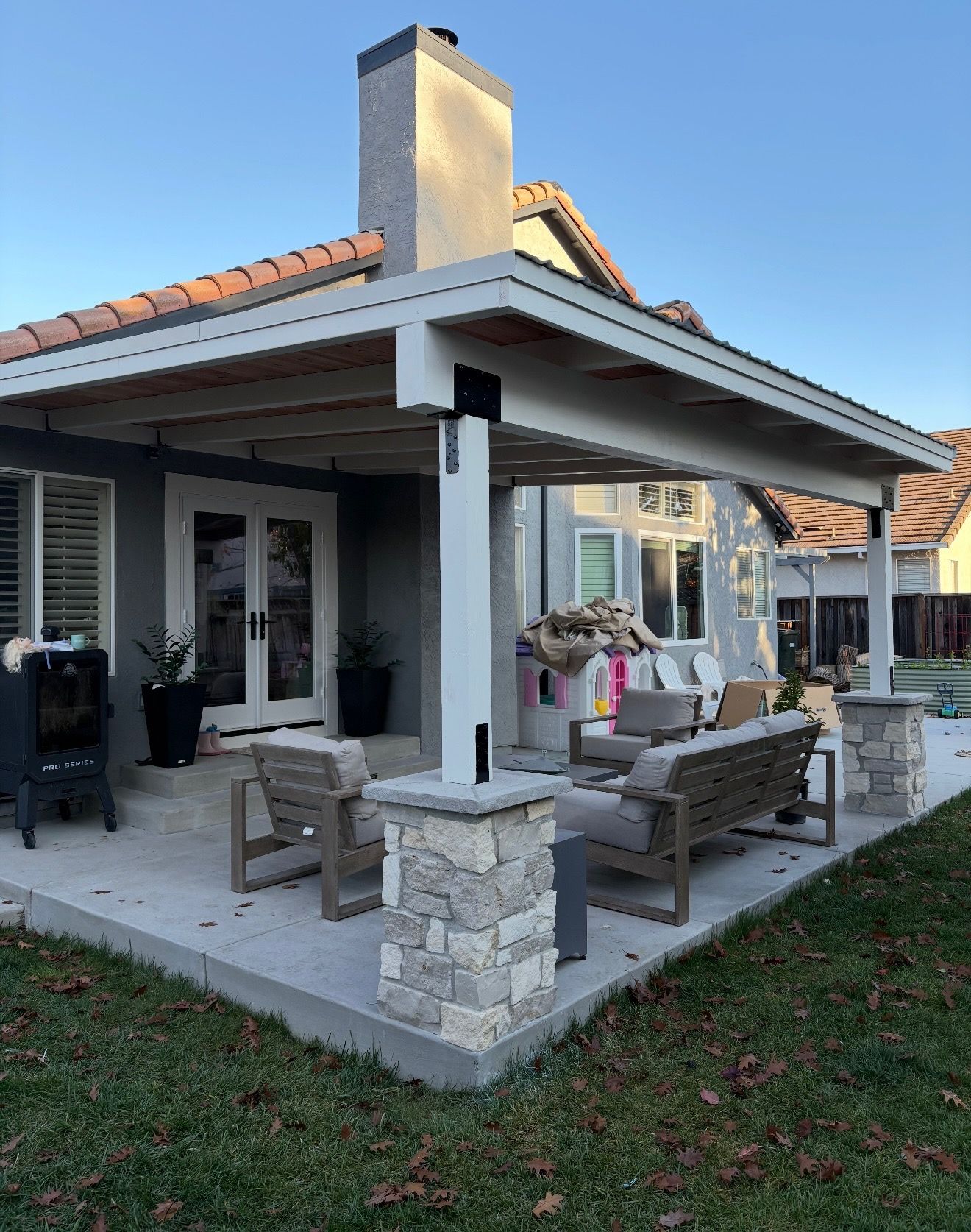 Covered patio with wicker seating and stone fireplace on a suburban house porch
