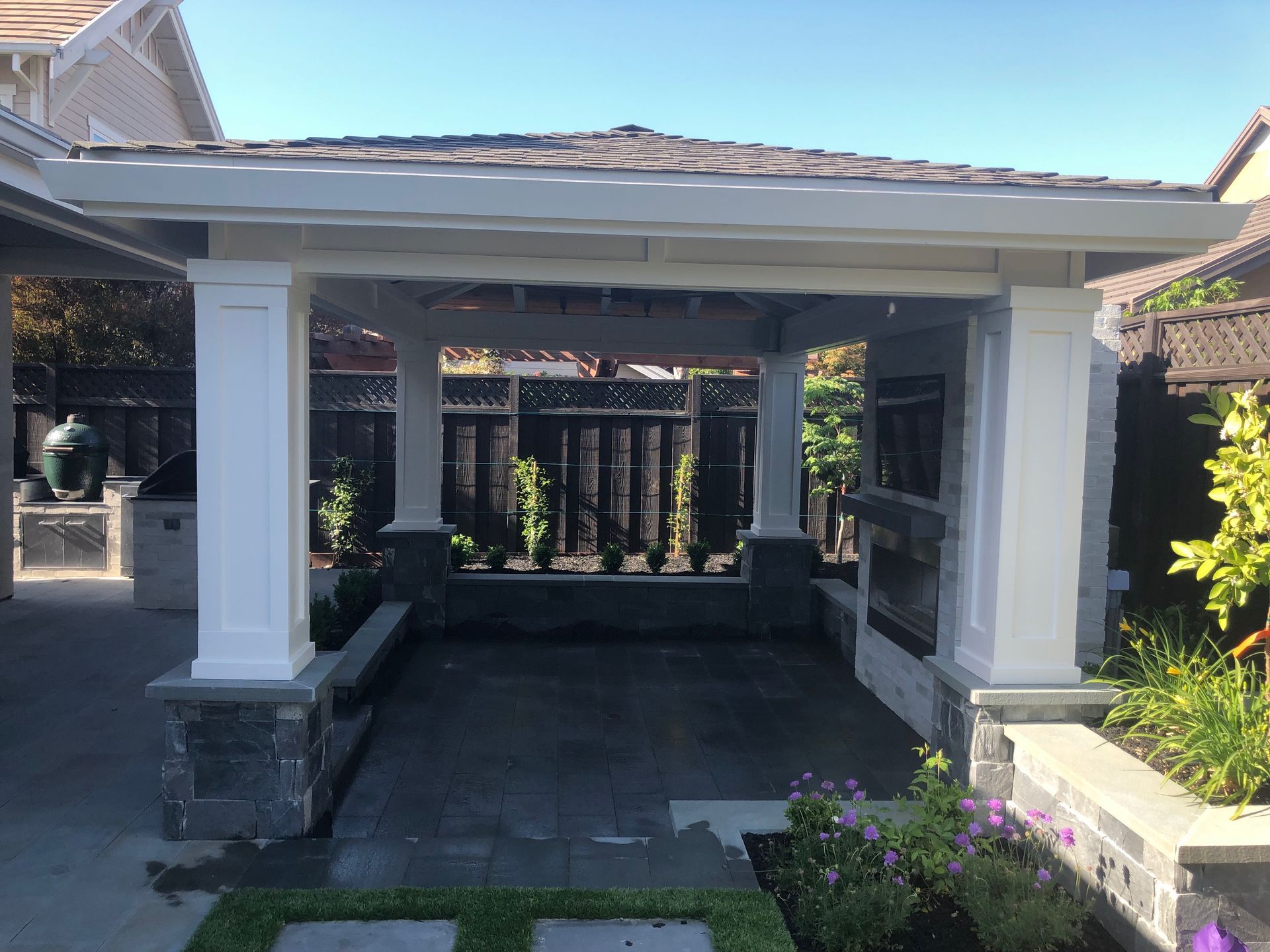 Covered front porch with white columns, dark tile floor, and landscaped garden