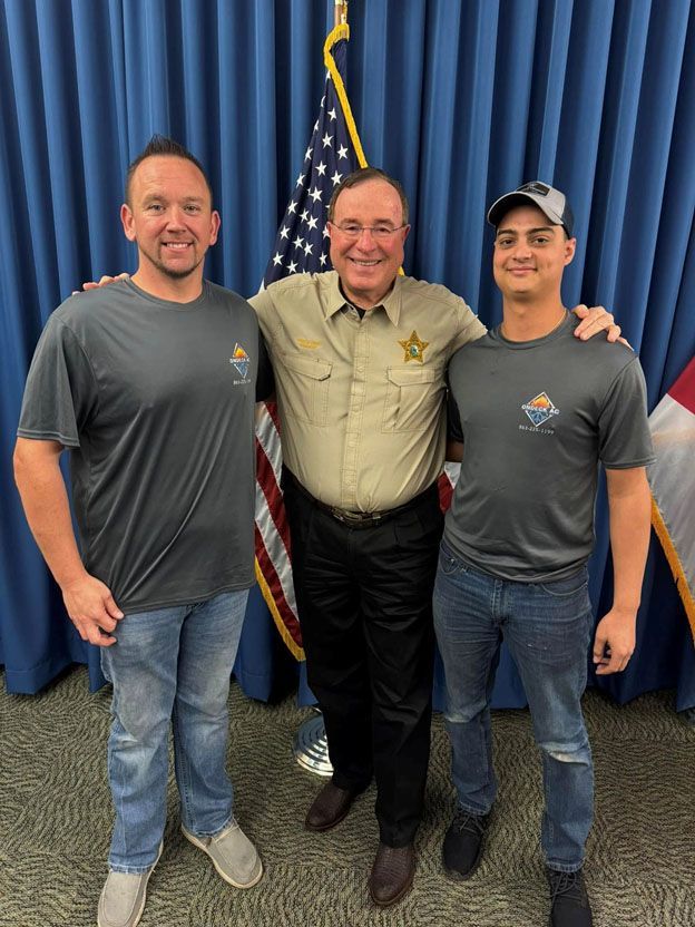 Three men are posing for a picture in front of an american flag.