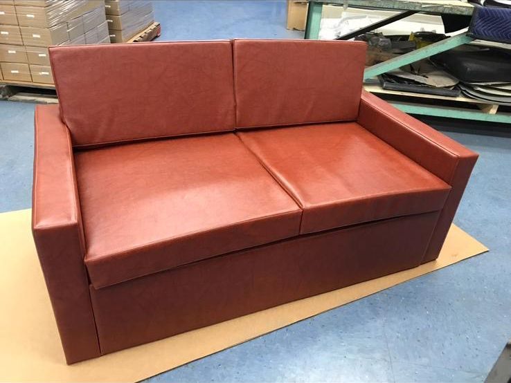 Red loveseat on a cardboard base in a warehouse.