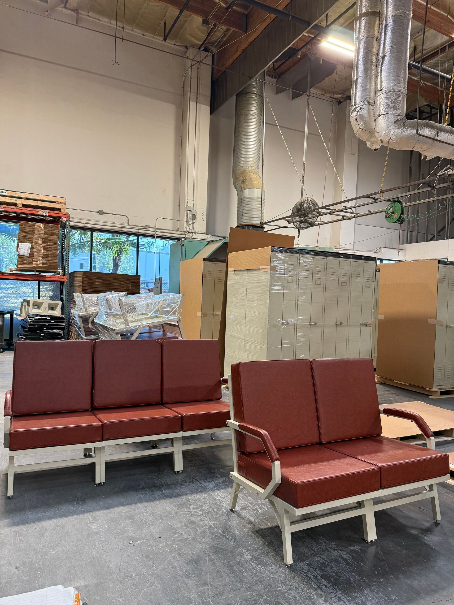 Two red leather couches in a warehouse setting.