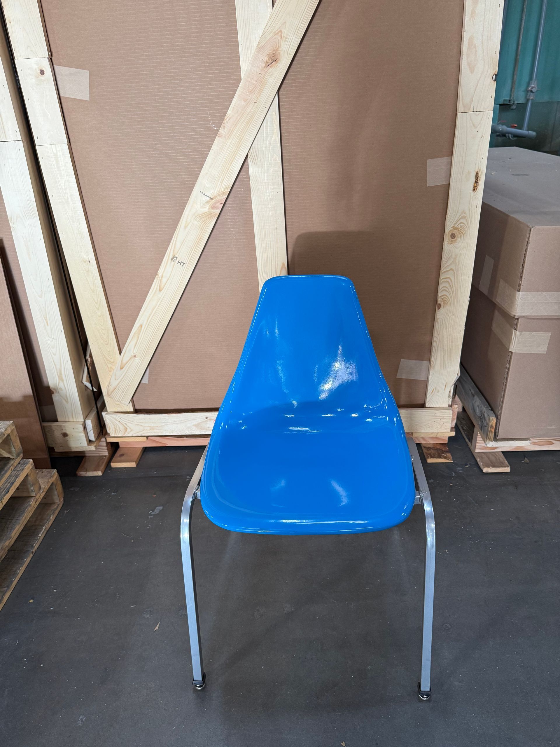 Blue plastic chair with silver legs against a wooden background.
