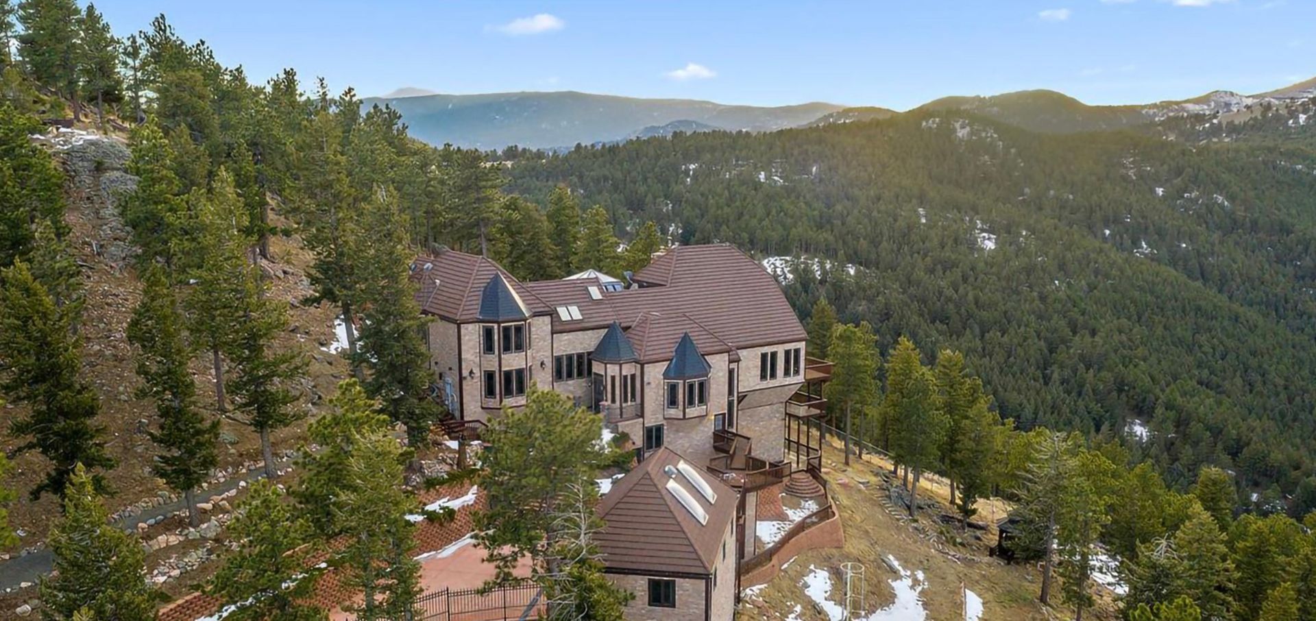 An aerial view of a large house on top of a hill surrounded by trees.