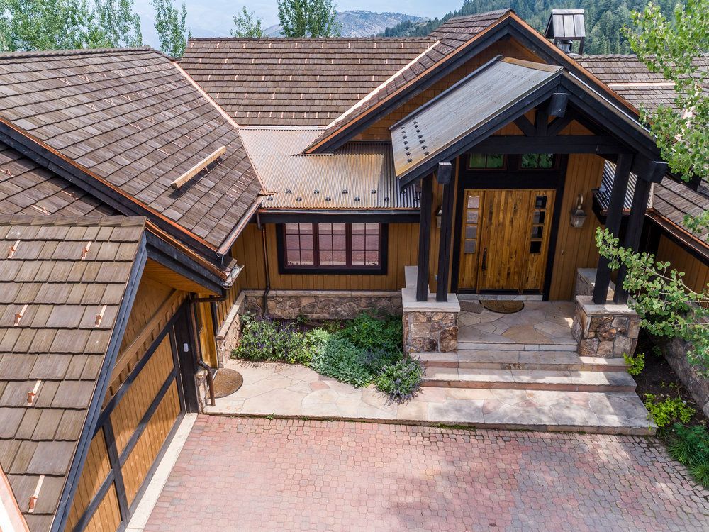 An aerial view of a large wooden house with a copper roof.