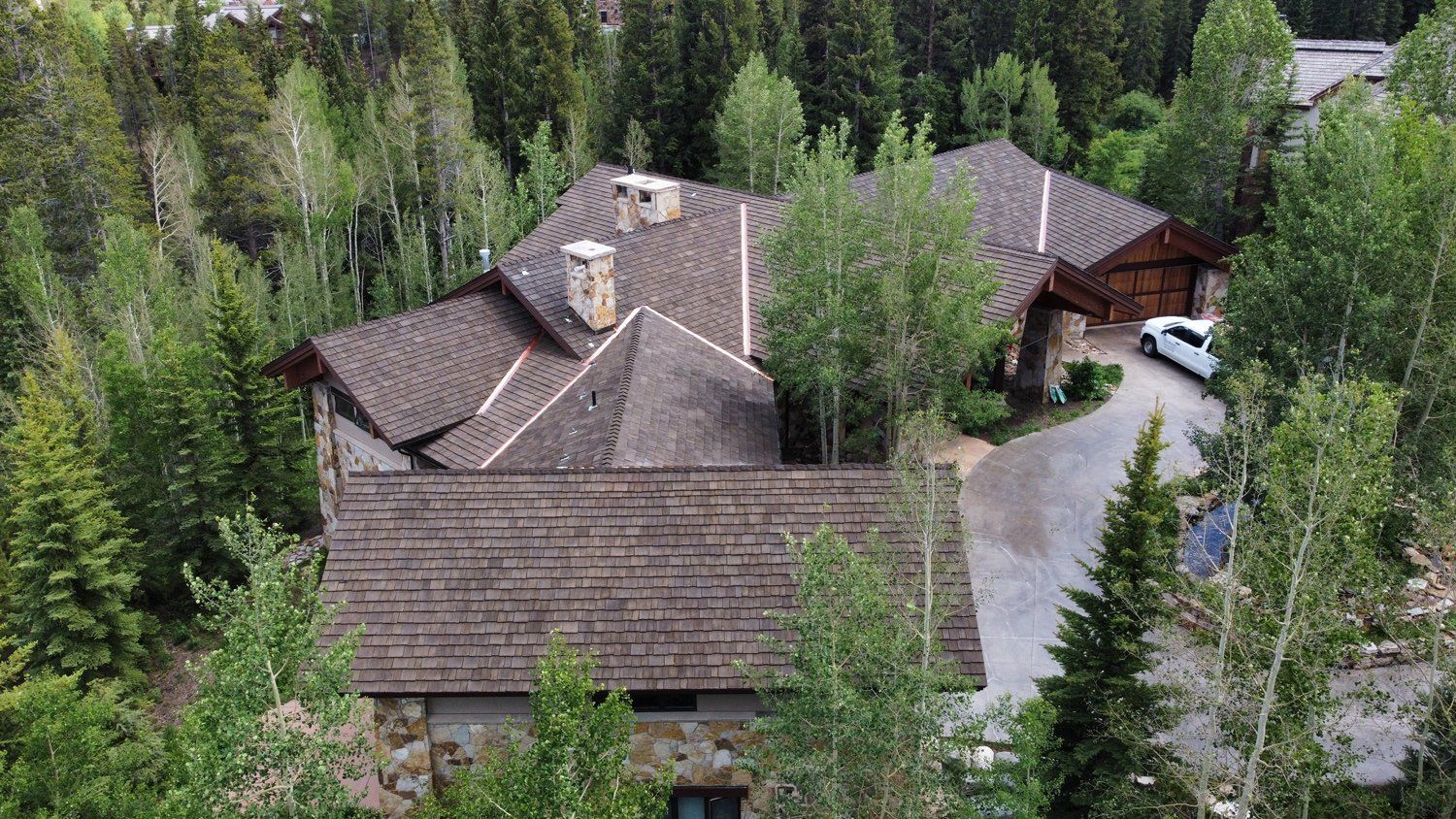An aerial view of a large house in the middle of a forest.