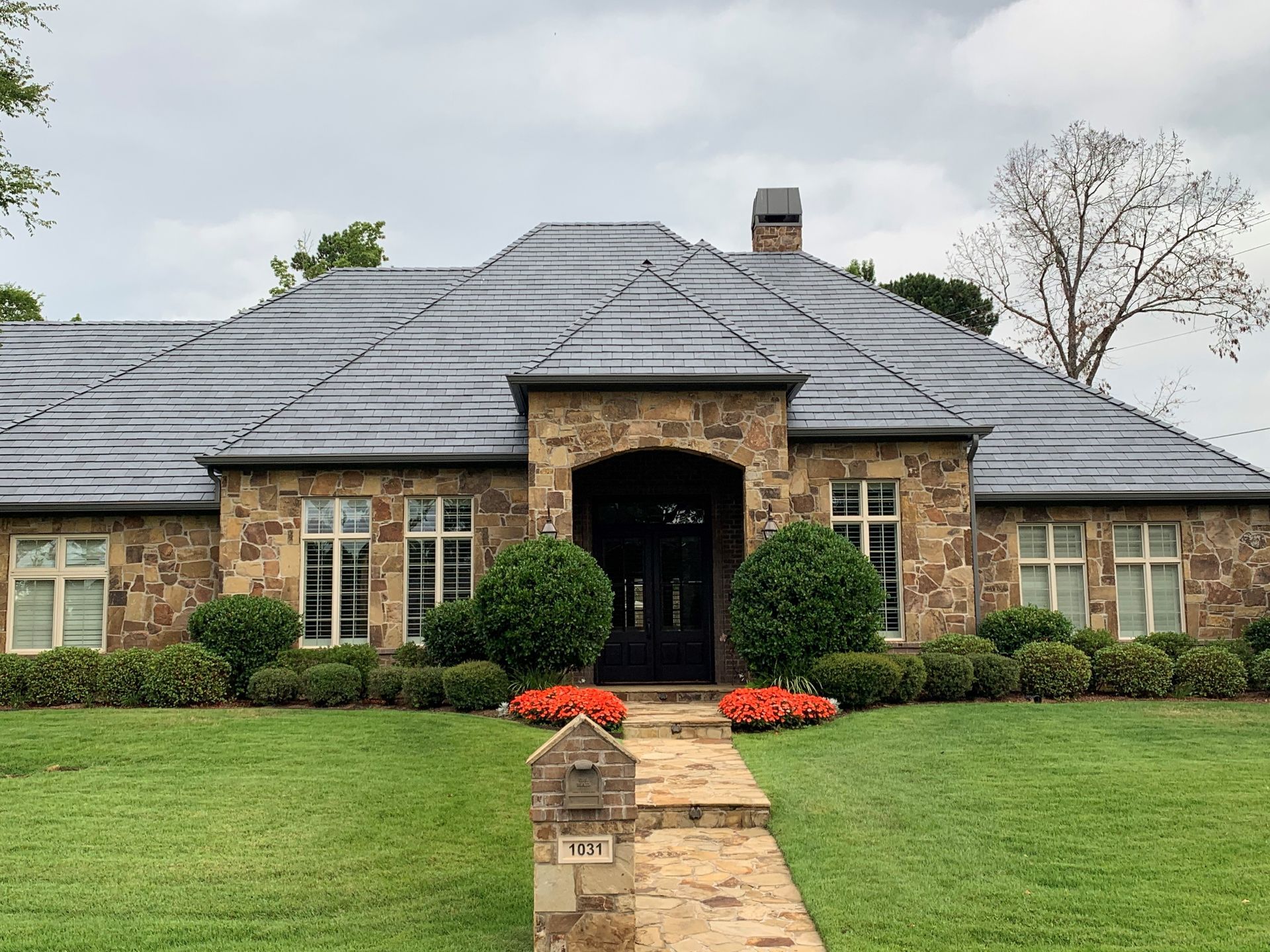 A large house with a slate roof is sitting on top of a lush green lawn.